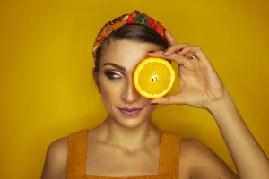 Kobieta z pomarańczą prezentująca owoce które maja w sobie naturalną witaminę C 
